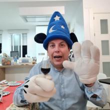 Yo con el gorro y guantes de Mickey en Fantasía sujetando una copa de vino